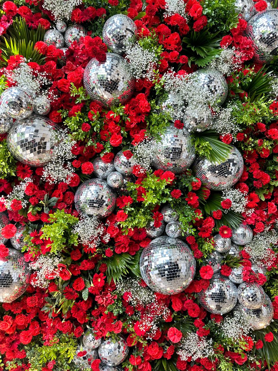 Modern photo booth wall with red flowers and disco balls