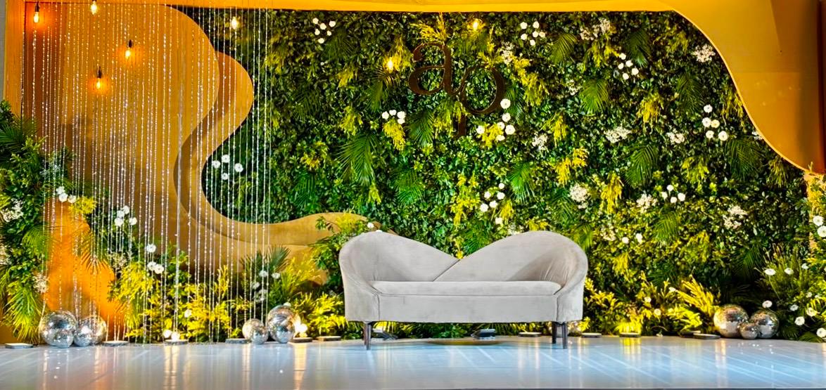 Luxury stage setup with gray sofa and greenery hedge wall